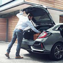 Muž otvára batožinový priestor v zadnej časti modelu Honda Civic 5D