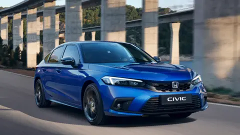 Modrý hybrid Civic idúci v horskej krajine.