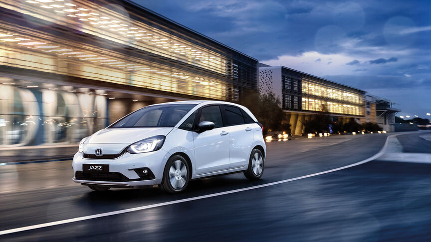 Trojštvrťový záber spredu na hybridný model HR-V pri jazde po vidieku