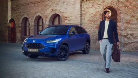 Muž prechádzajúci okolo vozidla ZR-V Hybrid SUV zaparkovaného v meste