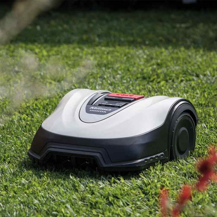 Trojštvrťový záber spredu na kosačku Honda Miimo na trávniku v záhrade