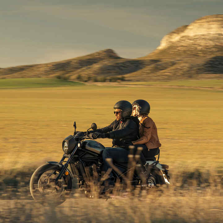 CMX1100 Rebel with rider and pillion on road at dusk