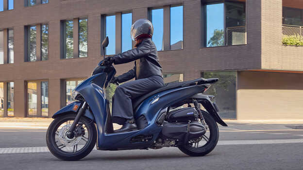 Pohľad zboku na model Honda SH350 s jazdcom v meste.