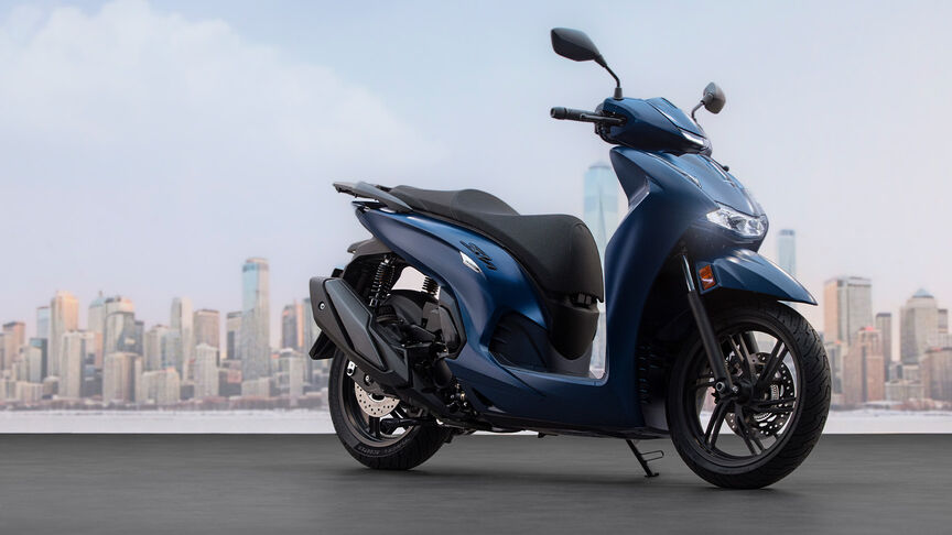 Pohľad zboku na ženu pri jazde na modeli Honda SH350i v meste.