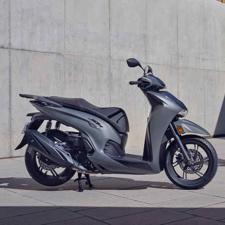Dva modely Honda SH350i stojace v zastavanej oblasti. 